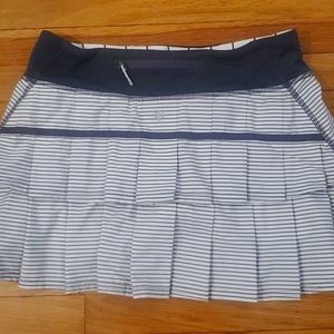 2 Lululemon tennis skirts. One is pink and white the other gray and white.